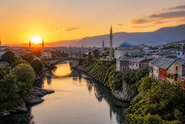 Balkanlar'da tarihi şehir merkezi ve nehir kıyısının gün batımında panoramik görünümü.
