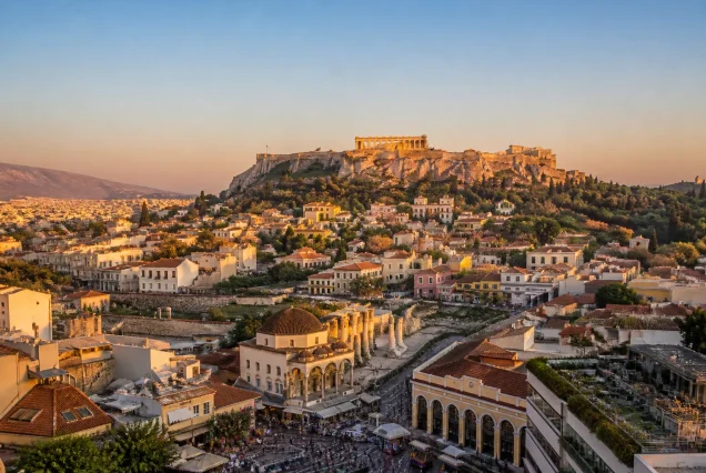 Atina şehrinin gün batımında panoramik görünümü, tarihi binalar ve mavi gökyüzüyle