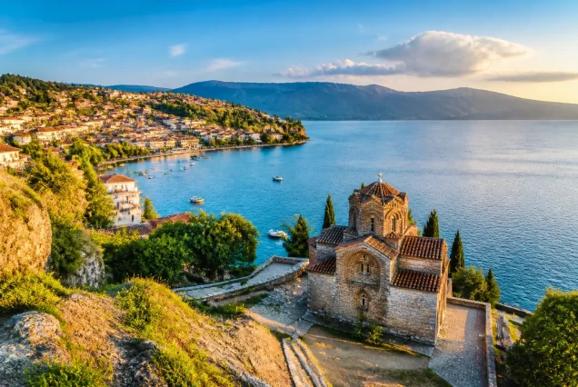 Balkanlarda Ohrid Gölü kenarında tarihi yapılar ve dağların gün batımında fotogerçekçi manzarası
