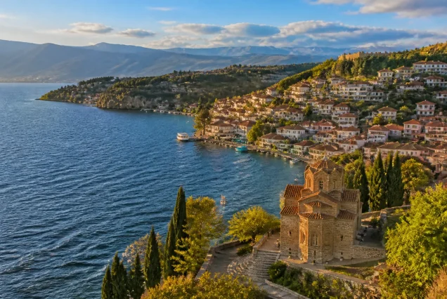 Balkanlarda Ohrid Gölü kenarında tarihi yapılar ve dağların gün batımında fotogerçekçi manzarası