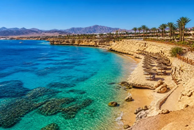 Mısır'ın Sharm El Sheikh şehrinde turkuaz renkte berrak deniz ve çöl manzarası ile güzel bir plaj görüntüsü.