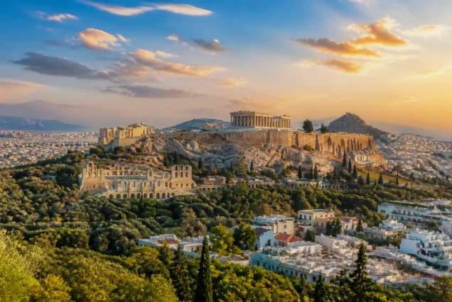 Atina şehrinin gün batımında panoramik görünümü, tarihi binalar ve mavi gökyüzüyle