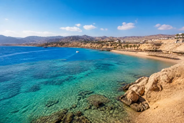 Mısır'ın Sharm El Sheikh şehrinde turkuaz renkte berrak deniz ve çöl manzarası ile güzel bir plaj görüntüsü.