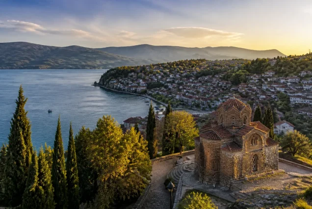Balkanlarda Ohrid Gölü kenarında tarihi yapılar ve dağların gün batımında fotogerçekçi manzarası