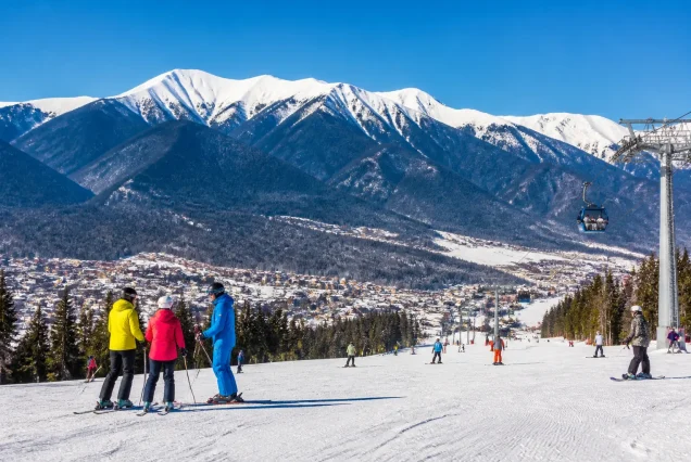 Bansko'da karlı dağlar ve kayak pistlerinde kayak yapan insanlar
