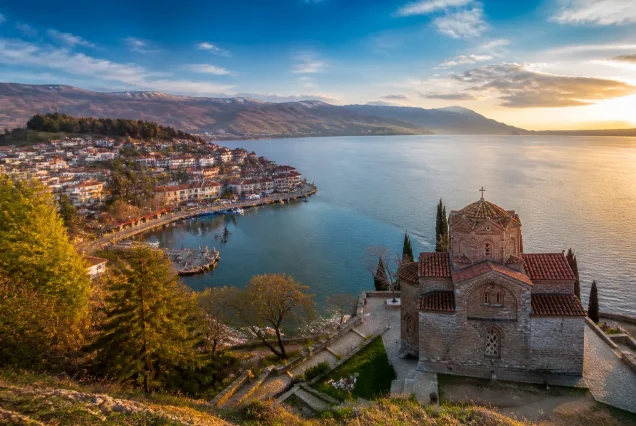 Balkanlarda Ohrid Gölü kenarında tarihi yapılar ve dağların gün batımında fotogerçekçi manzarası