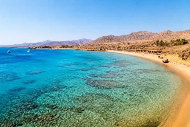 Mısır'ın Sharm El Sheikh şehrinde turkuaz renkte berrak deniz ve çöl manzarası ile güzel bir plaj görüntüsü.