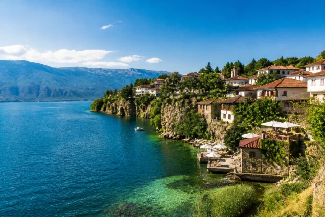 Balkanlar bölgesinde göl kıyısındaki tarihi evler ve çevresindeki doğal manzara