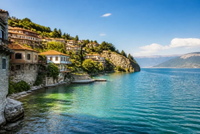 Balkanlar bölgesinde göl kıyısındaki tarihi evler ve çevresindeki doğal manzara