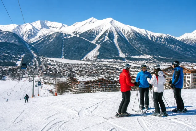 Bansko'da karlı dağlar ve kayak pistlerinde kayak yapan insanlar