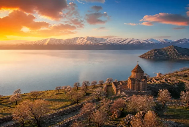 Doğu Anadolu bölgesinde karlı dağlar ve tarihi taş yapılar, geniş bir göl manzarasıyla birlikte