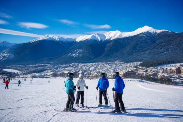 Bansko'da karlı dağlar ve kayak pistlerinde kayak yapan insanlar