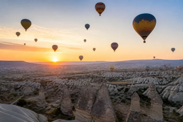 Kapadokya'nın gün doğumunda balonlarla kaplı peri bacaları manzarası