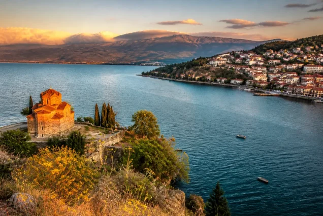 Balkanlarda Ohrid Gölü kenarında tarihi yapılar ve dağların gün batımında fotogerçekçi manzarası